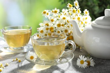 Tatlı papatya çayı ve çiçekler açık gri masada, yakın plan.