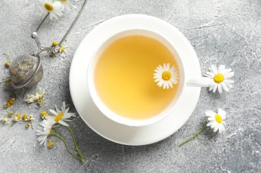 Lezzetli papatya çayı, zerk makinesi ve çiçekler açık gri masada, düz uzanmış.