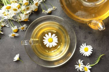 Lezzetli papatya çayı ve çiçekler gri masada, düz yatıyordu.