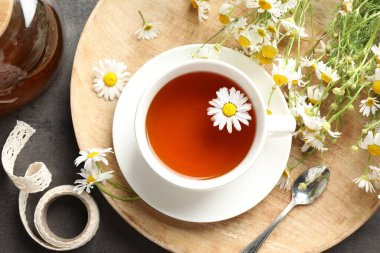 Lezzetli papatya çayı ve çiçekler siyah masada, düz yatıyordu.