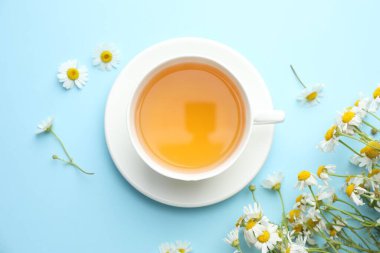 Lezzetli papatya çayı ve çiçekler açık mavi arka planda, düz yerde