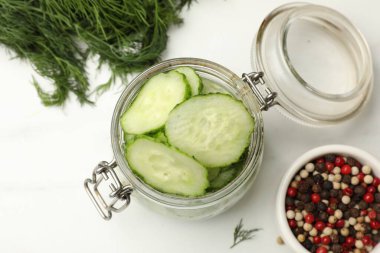 Turşu yapıyorum. Taze salatalık ve diğer malzemeler beyaz masada, düz yerde.