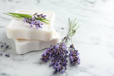 Sabun barları ve lavanta çiçekleri beyaz mermer masada, yakın plan. Metin için boşluk