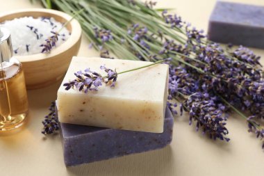 Aromatik sabun barları ve bej arka planda lavanta çiçekleri, yakın plan.