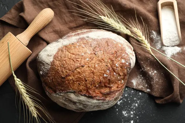 Bir somun taze ekmek, un, merdane ve sivri uçlu çiviler siyah masada, düz yatıyordu.