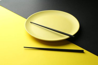 Renkli arka planda şık tabak ve çubuklar, yakın plan