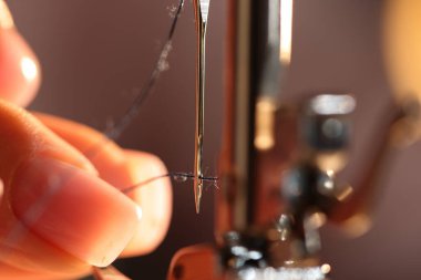 Bulanık gri arkaplanda dikiş makinesi iğnesi, makro görünümü olan kadın