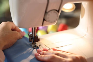 Bulanık arkaplan ve makro görünümde dikiş makinesiyle çalışan kadın