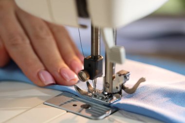 Bulanık arkaplan ve makro görünümde dikiş makinesiyle çalışan kadın