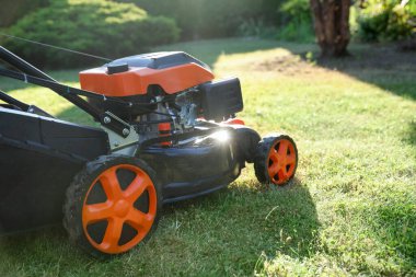 Bahçedeki yeşil çimlerin üzerinde bir çim biçme makinesi, yakın plan. Metin için boşluk
