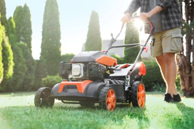 Bahçede çim biçme makinesiyle çimen biçen adam, yakın plan.