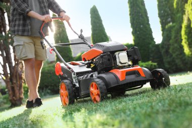 Bahçede çim biçme makinesiyle çimen biçen adam, yakın plan.