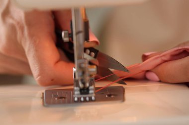 Atölyede dikiş makinesi ve kumaşla çalışan bir kadın.