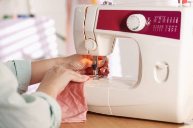 Atölyede dikiş makinesi ve kumaşla çalışan bir kadın.