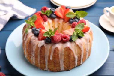 Böğürtlenli leziz kek, mavi ahşap masada jöle ve nane, yakın plan.