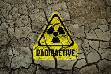 Çatlak kuru toprak üzerindeki sarı radyoaktif tabela, üst manzara. Radyolojik kirlilik