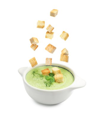 Beyaz arka planda çorba kasesine düşen kızarmış ekmekler.