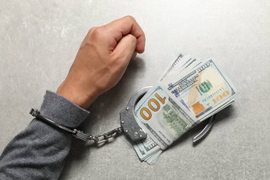 Yozlaşma. Elleri kelepçeli bir adam. Gri masa, üst manzara.