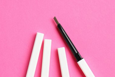 Açık pembe arka planda kaş kalemi kıvır, düz uzan.