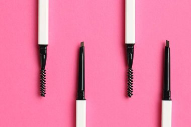 Açık pembe arka planda kaş kalemi kıvır, düz uzan.