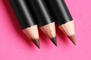 Pembe arka planda farklı kaş kalemleri, düz yatış.