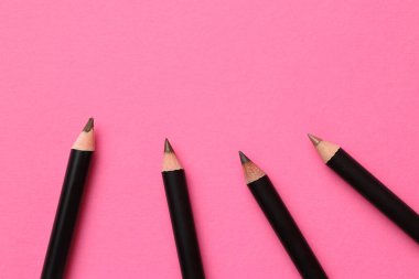 Farklı kaş kalemleri parlak pembe arka planda, düz yerde. Metin için boşluk