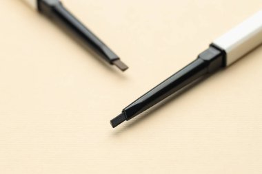 Bej arka planda otomatik kaş kalemleri, makro görünüm