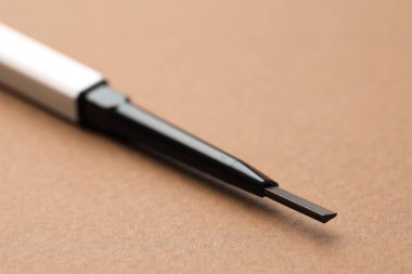 Kahverengi arka planda otomatik kaş kalemi, makro görünüm