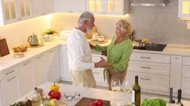 Mutfakta birlikte yemek pişirirken dans eden yaşlı çift.