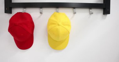 Açık mavi beysbol şapkasını beyaz duvara asan kadın, yakın plan.