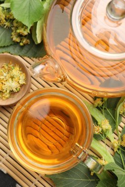 Tatlı ıhlamur çayı fincanda, çaydanlıkta, yapraklarda ve çiçeklerde bambu hasırında, düz yerde