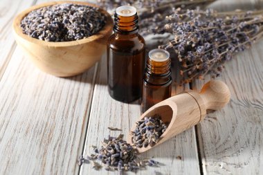 Beyaz ahşap masada doğal yağ ve lavanta çiçekleri, yakın plan.