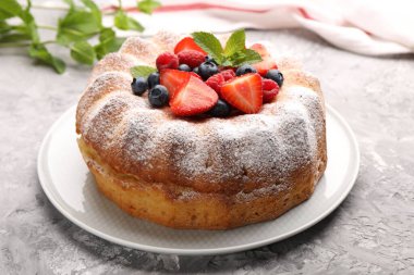 Gri desenli masada pudra şekeri ve böğürtlenli leziz kek, yakın plan.