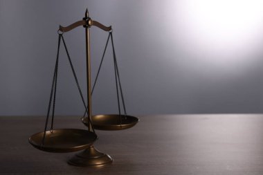 Gri arka planda, ahşap masada adalet terazisi. Metin için boşluk