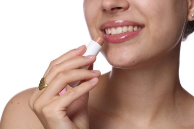 Beyaz arka planda dudak kremi olan genç bir kadın, yakın plan.