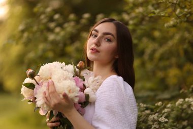 Parkta şakayık demeti olan güzel bir kadın.