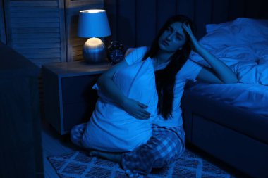 Evde yerde uykusuzluk çeken, yastıklı hayal kırıklığına uğramış bir kadın.