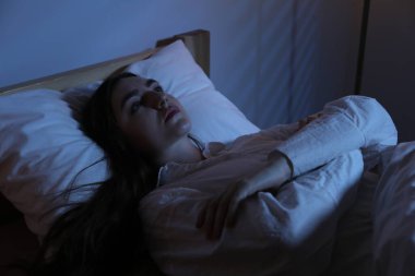 Evde yatakta uykusuzluk çeken hayal kırıklığına uğramış bir kadın.