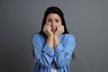 Gri arka planda panik atak geçiren kadın.