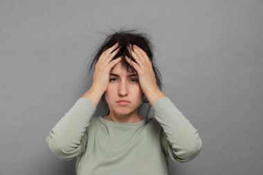 Gri arka planda akşamdan kalma bir kadın.