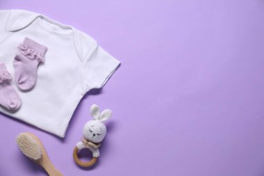 Menekşe arka planda bebek kıyafetleri ve aksesuarlar, düz yatış. Metin için boşluk