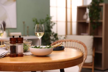 Bir kase salata, beyaz şarap ve baharatlar masanın içinde.