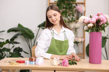 Çiçekçide şakayık buketi yapan bir çiçekçi.