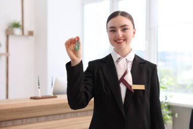 Üniformalı gülen resepsiyonist otelin misafir odasının anahtarını veriyor.
