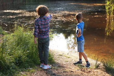 Çocuklar gölün kıyısında vakit geçiriyorlar doğada, arka planda