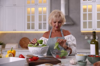 Mutfaktaki masada yemek pişiren son sınıf kadını.