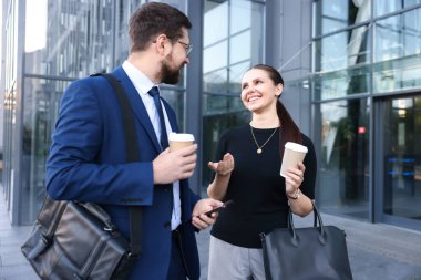 Kahveli mutlu iş arkadaşları ofis binasının yakınında bir şeyler tartışıyorlar.