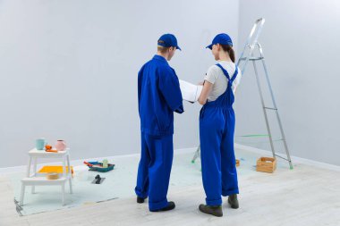 Tasarım projesine bakan işçiler odada, arka planda