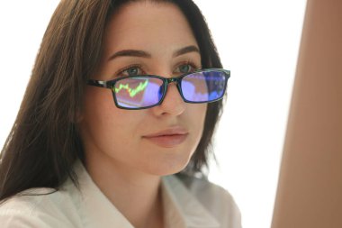 Kapalı mekanda yansımalı gözlük takan genç bir kadın.