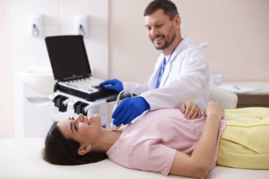 Klinikte kadının tiroid bezini ultrason taraması yapan sonograf.